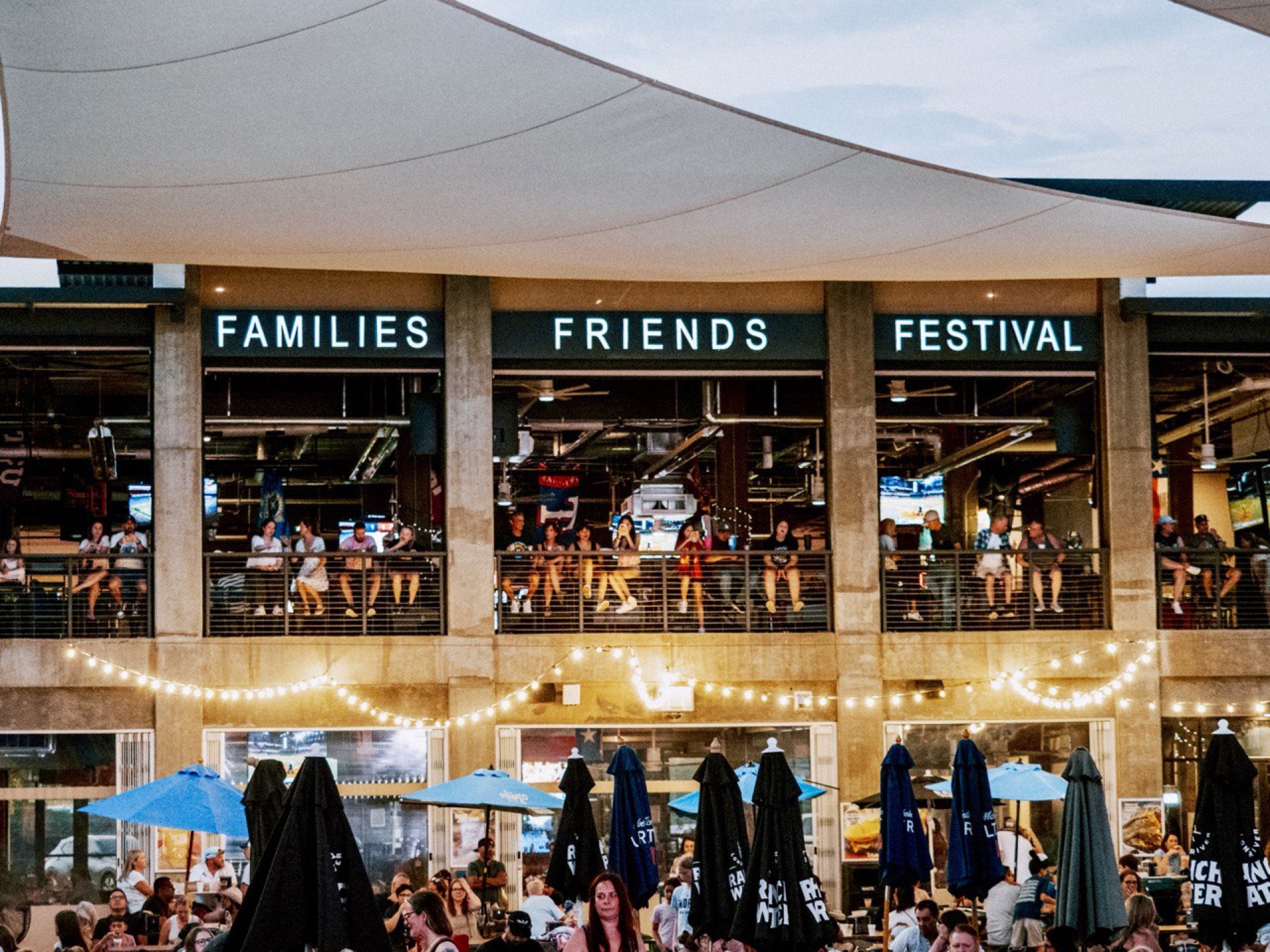 Two-story building at dusk with string lights and crowds