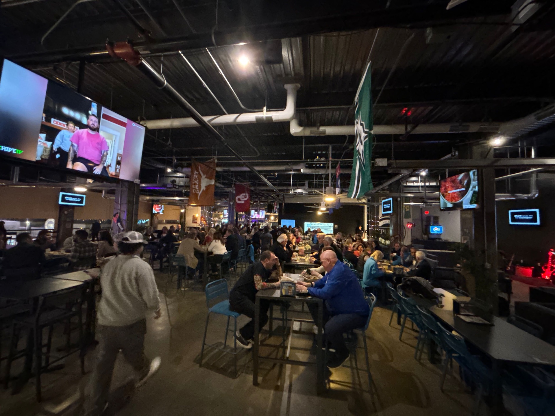 Indoor bar at night with dinner crowd and multiple screens